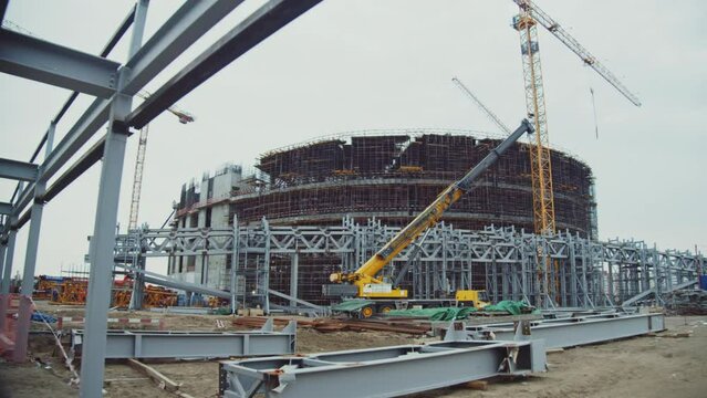 Metal carcass and huge roof details near future sports arena at construction site under overcast sky. Building technology