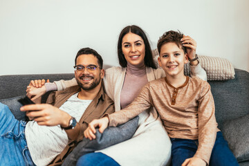 Young family watching TV together at home and having fun together.