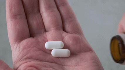 Man taking painkiller or analgetic pills on male hand pouring tablets from meds bottle. Taking medicine, health care, pharmacy and treatment concept. Close up - Powered by Adobe