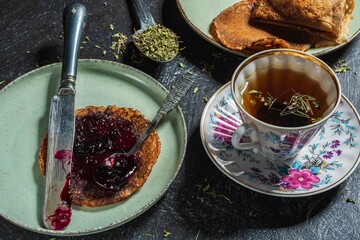 Still life - blueberry jam, green tea and pancakes. Food and drink on a dark background