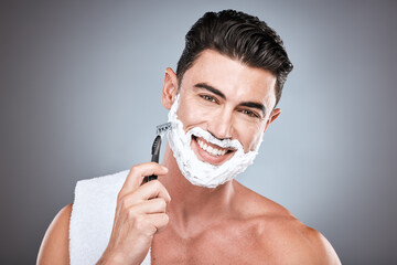 Razor, face and man with shaving cream in studio isolated on a gray background. Beard, towel and...