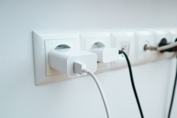 Many chargers plugged into maltiple electrical outlet on white background. Concept of electricity consumption.