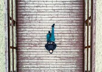 Aerial view landscape. A person lying on a wooden footbridge. Photo from a drone.