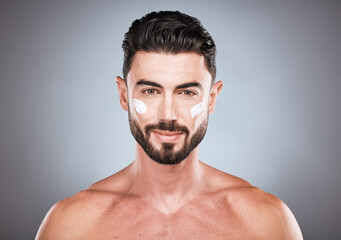 Face portrait, skincare cream and man in studio isolated on a gray background for wellness. Cosmetics, dermatology and young male model with lotion, creme or moisturizer product for facial health.