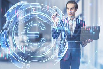 Thoughtful young european businessman with laptop computer using glowing euro hologram on bright blurry office interior background. Money, digital banking and finance concept. Double exposure.