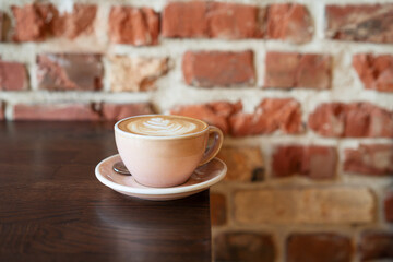 Pink cup with coffee in front of brick wall. Morning coffee background
