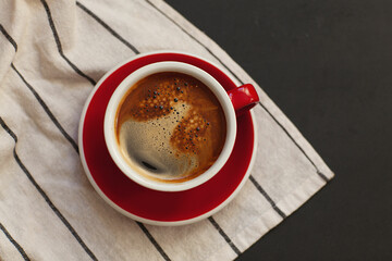 Red cup with hot coffee and thick foam on a black background. coffee shop concept
