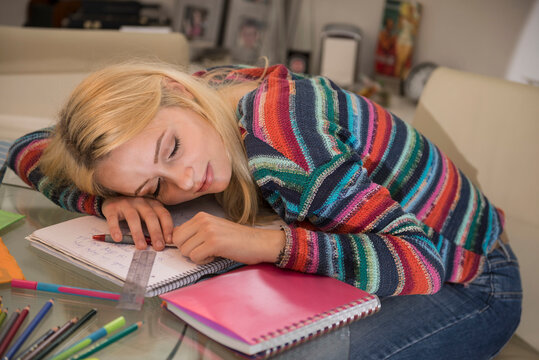 Exhausted student sleeping during doing homework in the living room, Bavaria, Germany