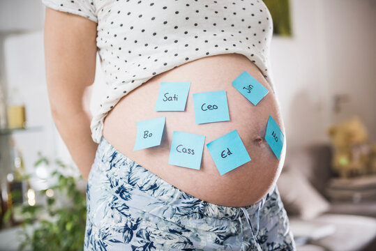 Pregnant woman with baby names on belly, Munich, Bavaria, Germany