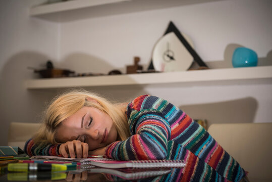 Exhausted student sleeping during doing homework in the living room, Bavaria, Germany