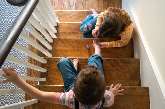 Quiet moment of sister giving brother a pedicure on the stairs