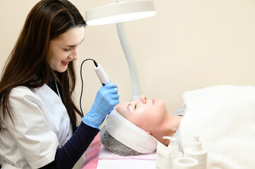 A beautician performs a rejuvenating mesotherapy procedure using dermapen.