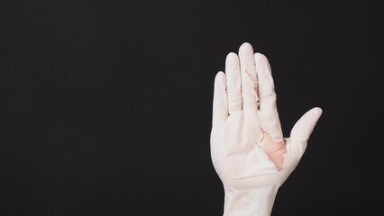 Hand Wearing torn latex glove or torn rubber gloves on black background.