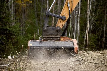 Attachable excavator forestry mulching head destroys roadside vegetation.