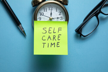 Self care time on sticky note with a clock and business objects.