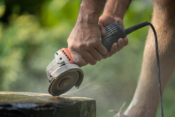 Worker using an angle grinder sanding and grinding concrete surface outdoor