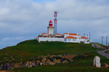 Fototapeta na wymiar Lighthouse and Atlantic ocean at Cape Roca (Cabo da Roca). Western point of Europe. Tourists enjoying amazing landscape on Cabo da Roca