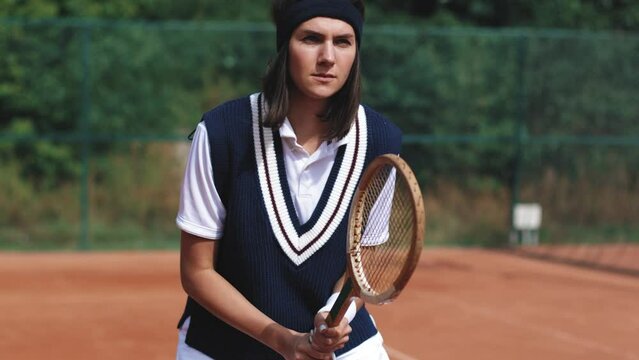 4k video. Young and beautiful sporty brunette woman playing tennis in clay court. Amatour frienship match. Vintage and retro racket. Natural tree background.