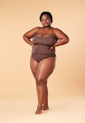 Portrait, wellness and plus size with a model black woman posing hands on hips in studio on a beige...
