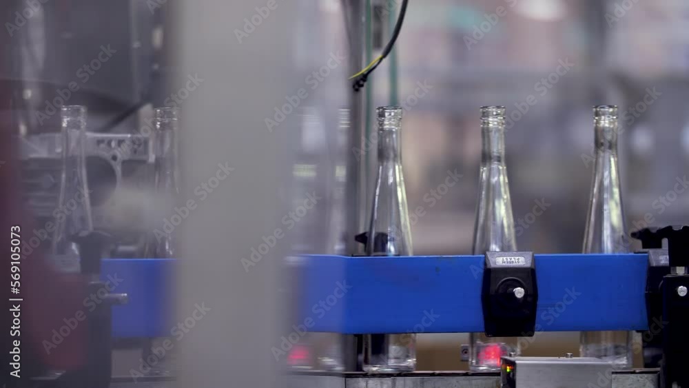 Poster empty slender wine bottles carried by an automated conveyor belt from one part to another of a winer