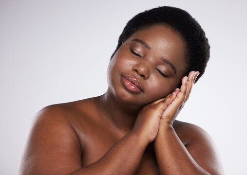 Relax, skincare beauty or black woman with makeup or cosmetics isolated on a gray studio background. Hands, face or African plus size model resting with spa facial products for self love or care
