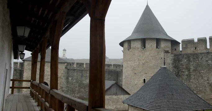 the courtyard of the Khotyn fortress with a loggia, a balcony with wooden columns against the background of the towers of the castle in Khotyn. rain