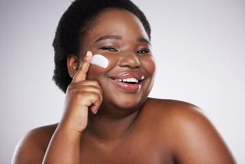 Portrait, skincare and cream with a model black woman in studio on a gray background for plus size beauty. Face, skin and lotion with an attractive young female indoor to apply facial treatment