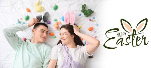 Festive banner with happy young couple with bunny ears and Easter eggs on bed