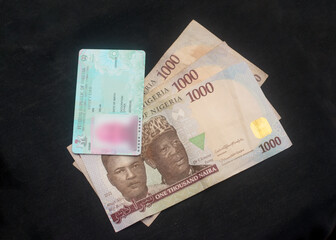 Nigerian voter's card placed on multiple naira notes, cash or money, depicting illegally vote buying during elections in Nigeria