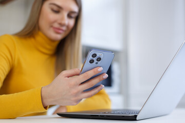 Beautiful young blonde woman browsing mobile app on modern smart phone. White female person using blue mobile phone for communication online