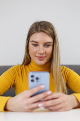 Beautiful female person typing a message on modern smart phone. Portrait of cute white woman with long blonde hair using a mobile phone app