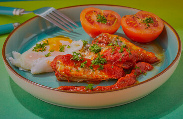 Sardines in tomato sauce with poached egg and tomatoes.