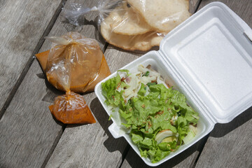 Indonesian salad with lettuce and steamed vegetables served with a peanut sauce dressing, take away package