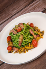 Recipe for spaghetti with spinach cream and smoked bacon, tomatoes and chanterelle mushrooms. High quality photo