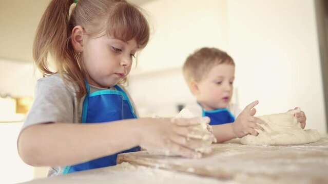 kids are baking. children knead dough and flour in the kitchen. happy family kid concept. baby children bake pizza dough. brother sister baking cookies. teamwork children knead dough and dream flour