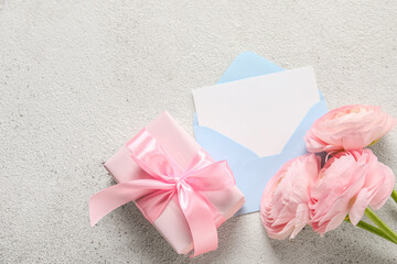 Composition with gift box, blank card and beautiful ranunculus flowers on light background