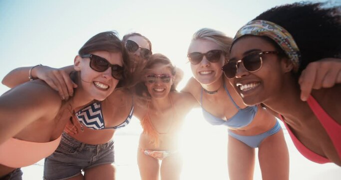 Row of friends at the beach together in swimwear posing for a summer picture in slow motion