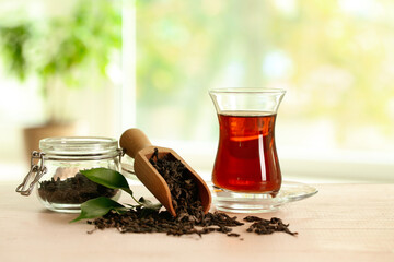Cup of Turkish tea and scoop with dry leaves on table