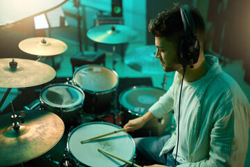 Music, drums and instrument with a man musician in a studio for a recording, performance or practice. Art, band and sound with a young male drummer expressing musical or artistic talent in a studio - Powered by Adobe