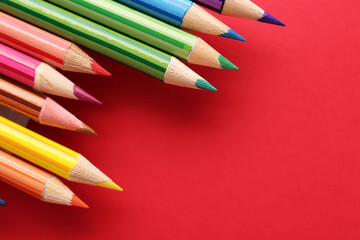 Set of colorful pencils on red background, closeup