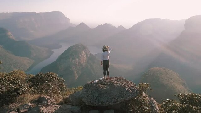 Rear view dolly shot of female hiker looking at view while standing on mountain against clear sky during sunny day