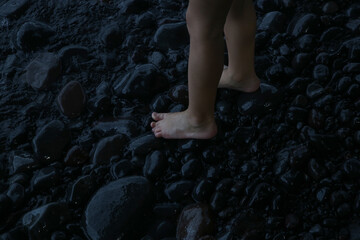 Child's feet barefoot on pebble beach near sea. Walking barefoot strengthens the muscles in children's feet and ankles, improving balance and posture and foster a connection with nature.