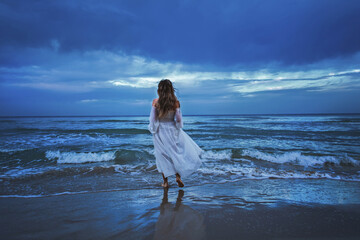 Fototapeta na wymiar Woman in white dress on a sea backgorund