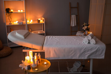 Interior of dark spa salon with couch, shelving units and burning candles
