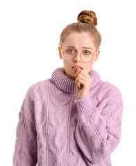 Young woman in sweater biting nails on white background