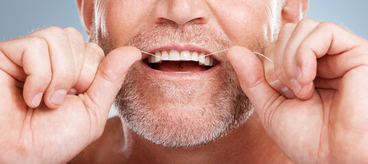 Closeup, floss and man with dental health, cleaning teeth and fresh breath against grey studio...