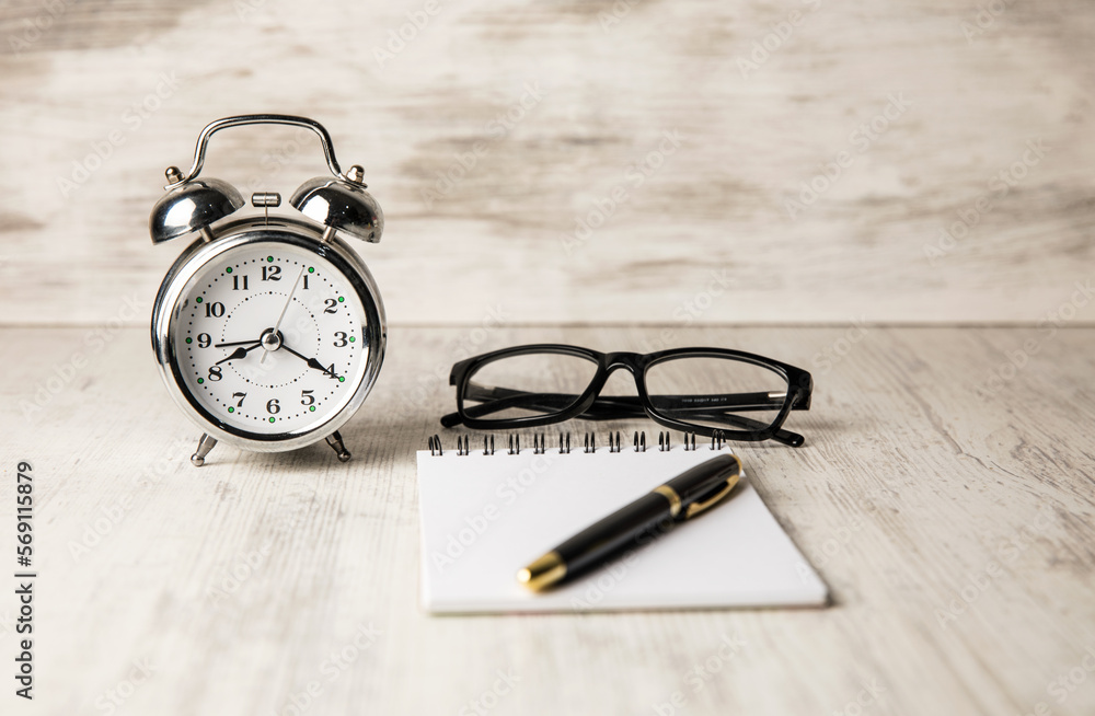 Poster alarm clock, очки and notebook on the table