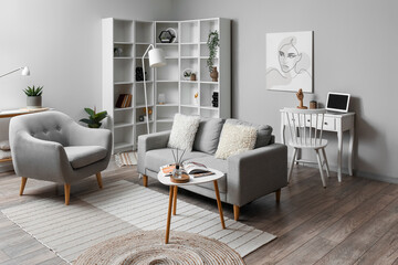 Cozy interior of living room with grey sofa, armchair and magazine on table