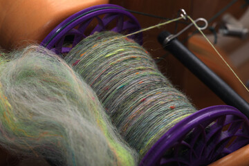 Spindle with hand spun organic sheep wool on a spindle on a traditional spinning wheel for yarn...