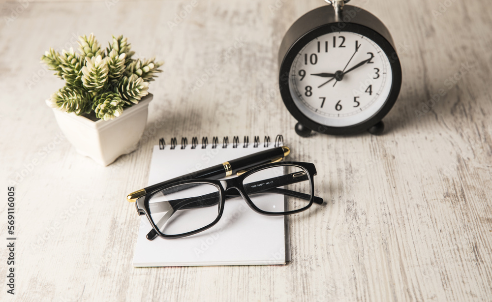 Poster alarm clock, очки and notebook on the table